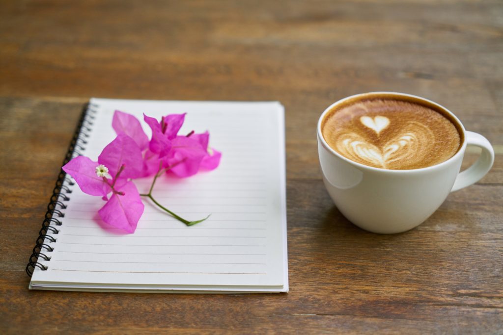 coffee and notepad with petals on top