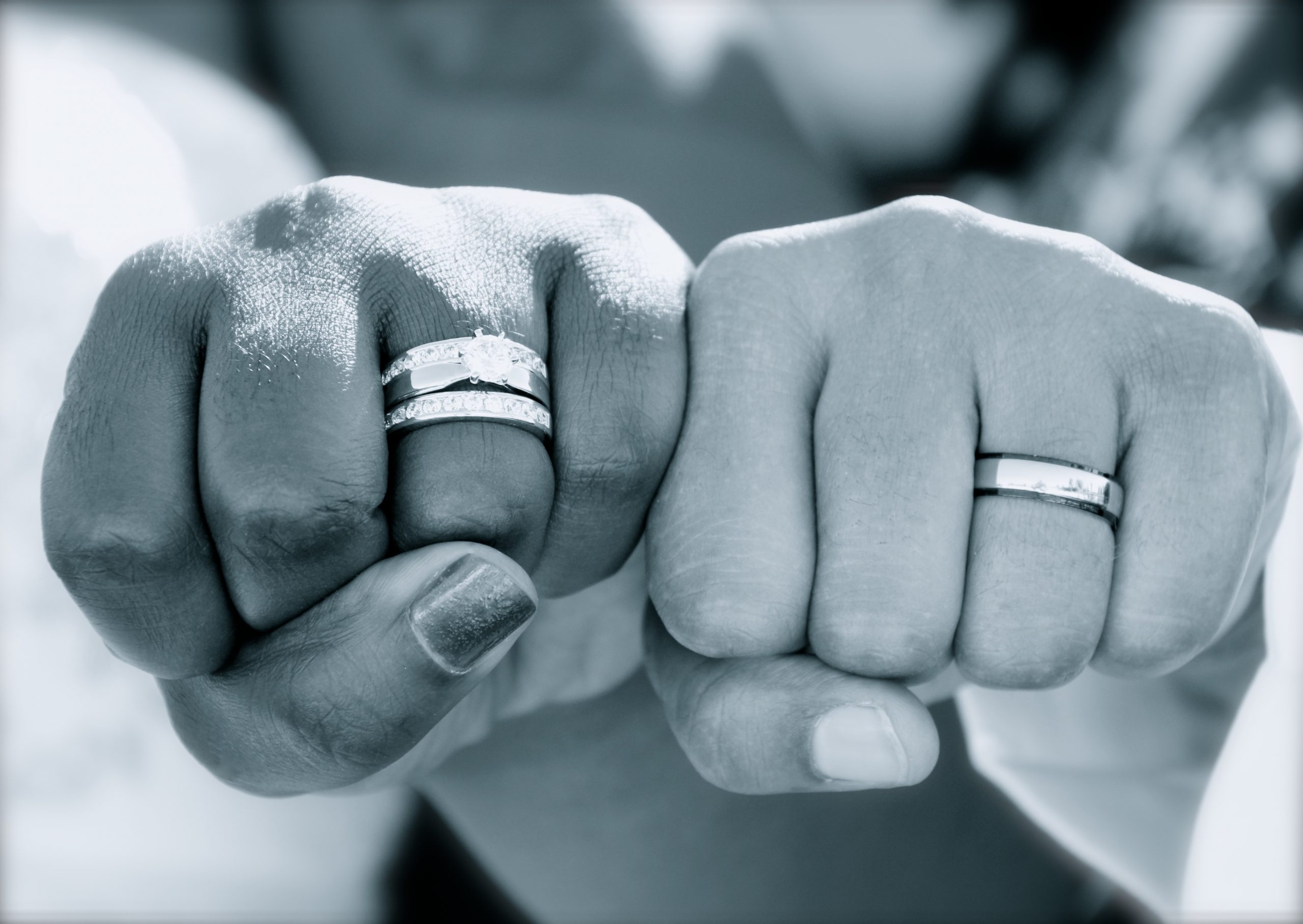 women holding out fists with wedding rings